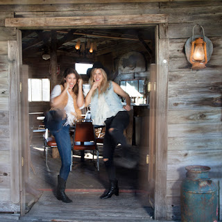 Two girls dressed in western clothing kick down a saloon style door at the Austin, Texas Ghost Town, JLorraine in Manor