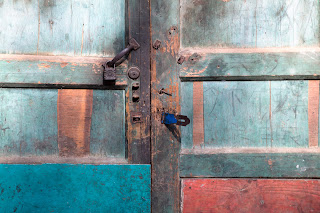 A beautifully colored door detail showing red and green paint and rusted locks from a door in Guilin, China.