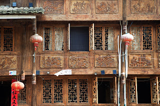 Traditional Chinese building, showcasing an ornately carved facade with lanterns in the windows. 