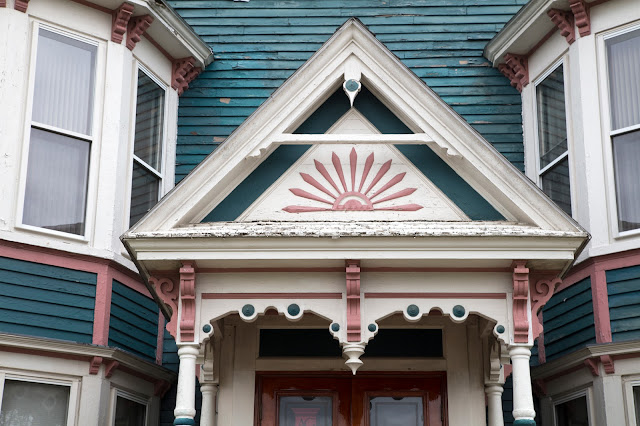 An architectural detail of an entryway to a peeling painted lady Victorian style home in Dover, New Hampshire