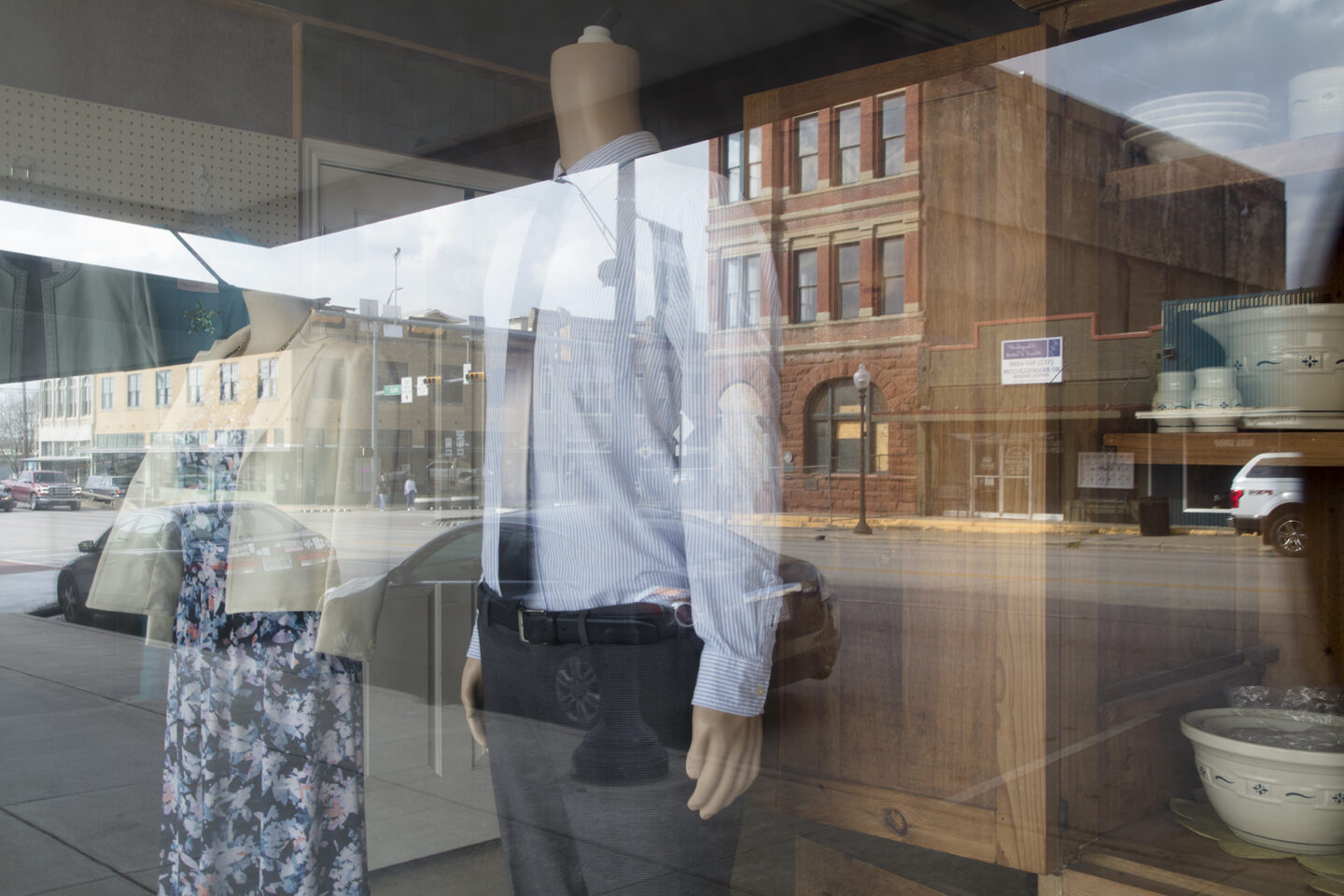 Reflections of a shop window in downtown Taylor, Texas featuring his and her mannequins 