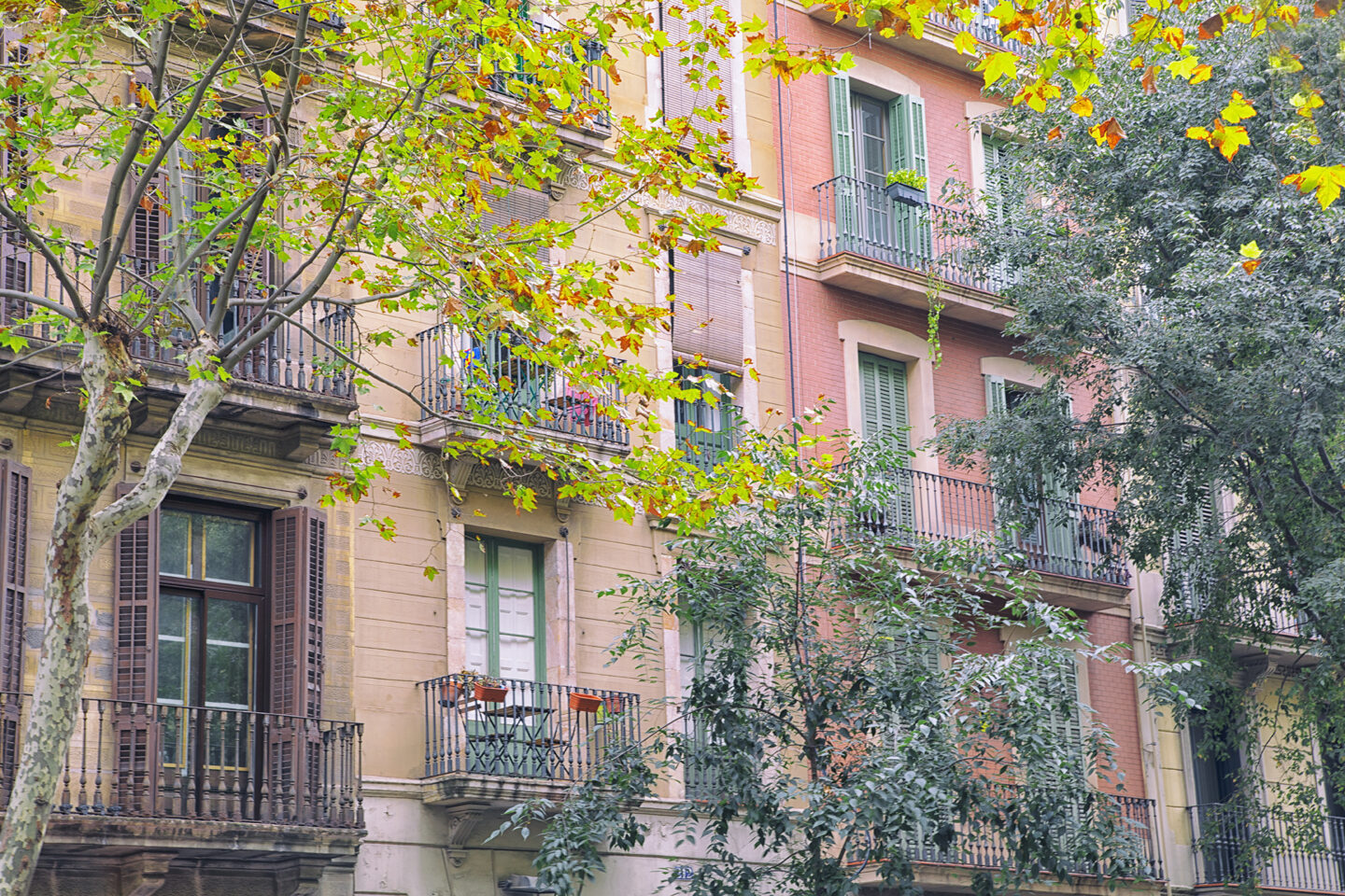 Building painted pink and green featuring iconic balconies, typical of Catalan architecture, as photographed by Carol Schiraldi, Barcelona, Spain 