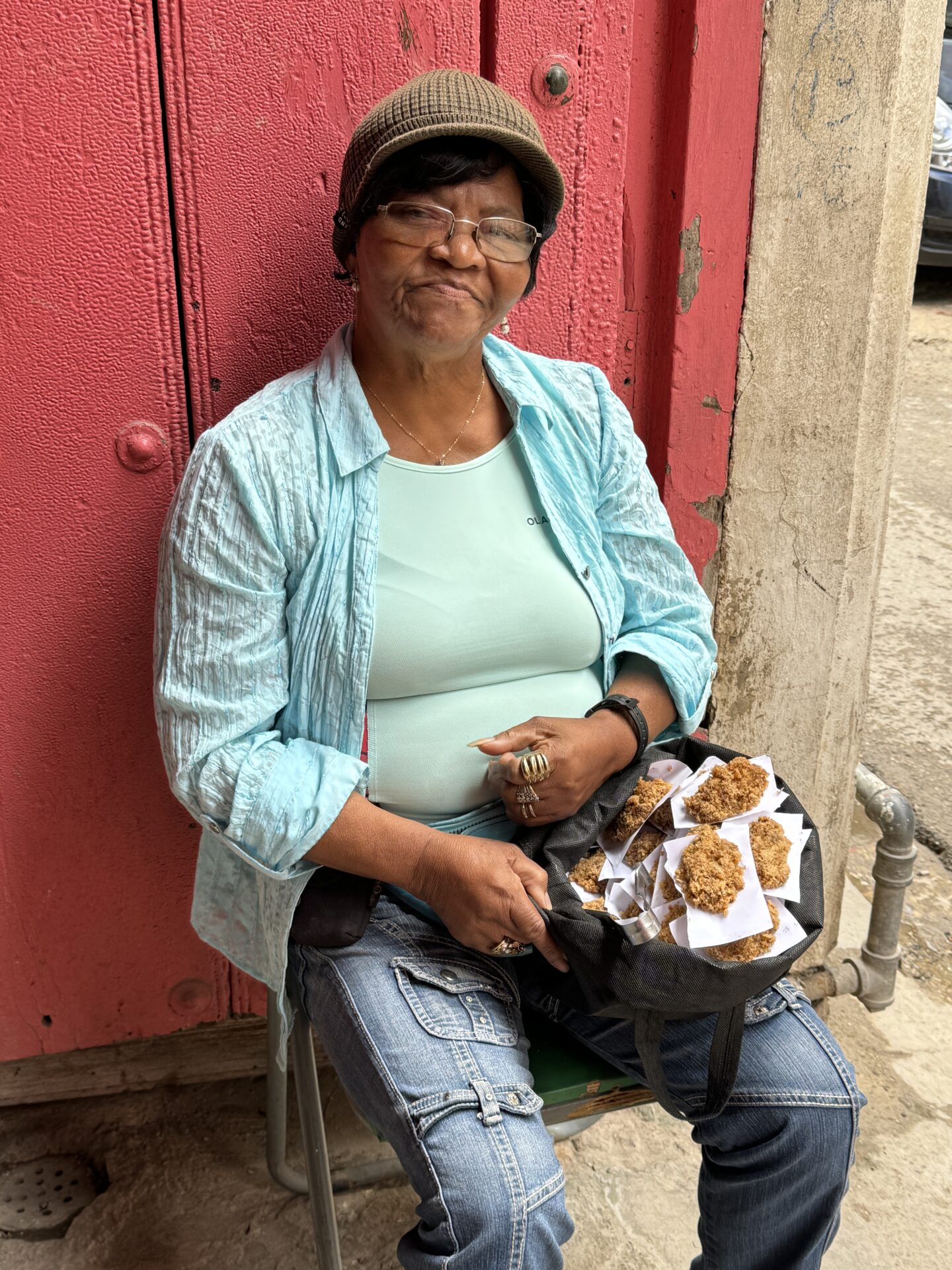 Woman selling sweets in the doorway of a building, Old Havana, Cuba, 2024, as photographed by Carol Schiraldi of Carol's Little World. 