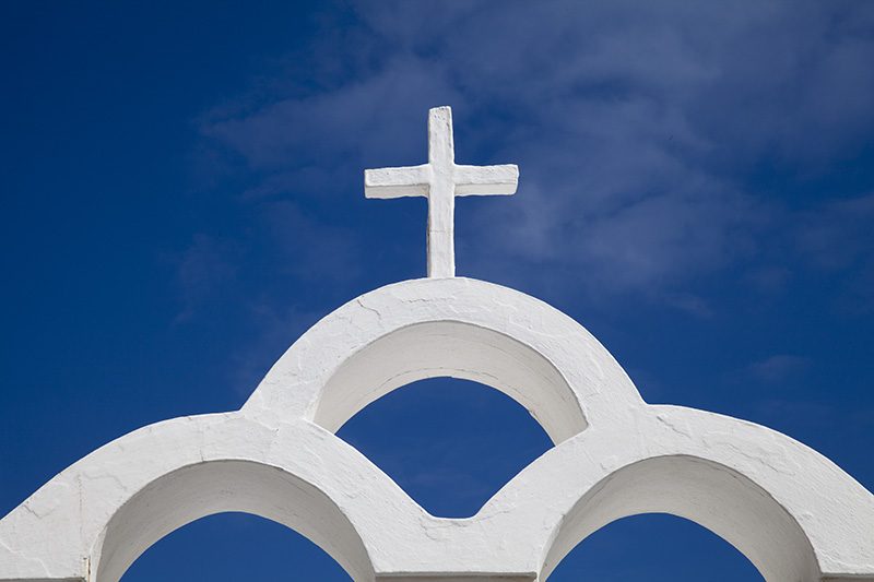 White cross set against blue sky on the Island of Santorini, Greece.