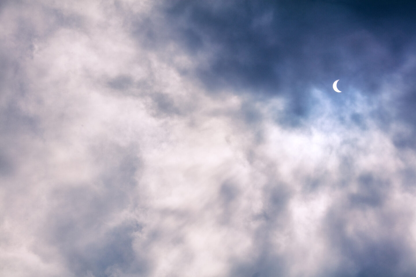 Crescent sun in a cloudy sky, taken during the total solar eclipse of 2024 by Carol Schiraldi in Texas. 