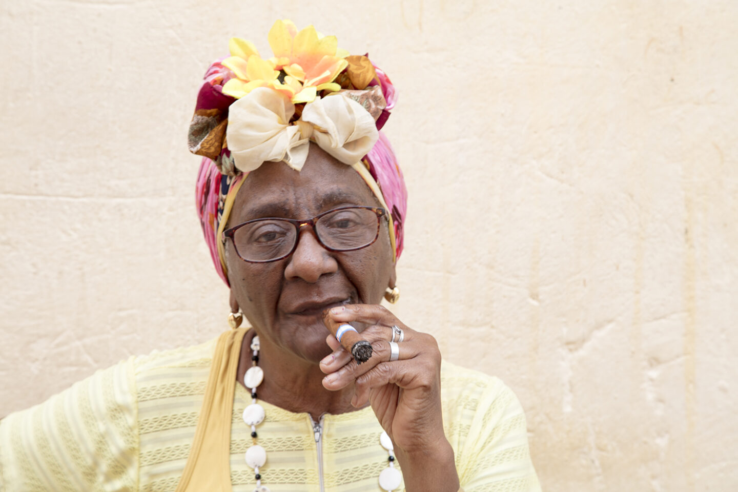 A soft yellow portrait taken in Havana Cuba of a woman enjoying a cigar from the Portraits of Cuba series 