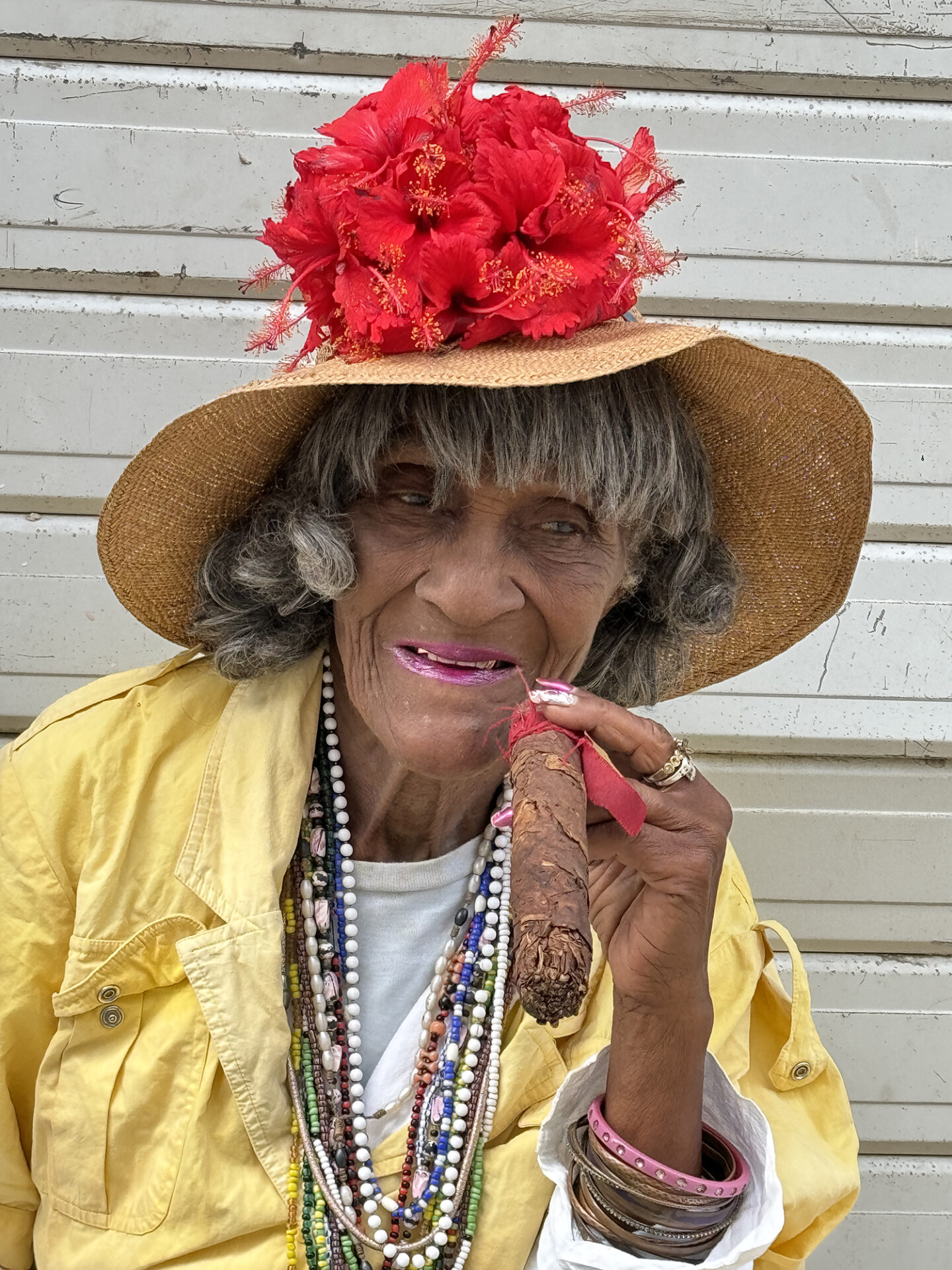 Portrait of a women wearing a hat with red flowers adoring it in Havana Cuba from the Portraits of Cuba series. 