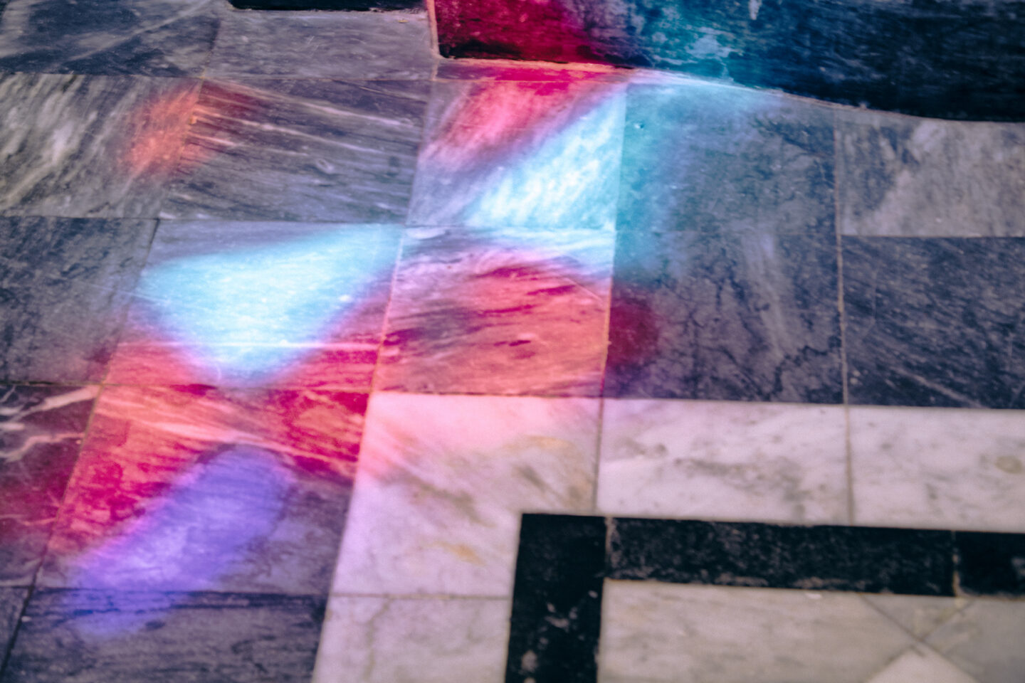 A stained glass window reflects on the floor of a church from the Curiosity Factory 