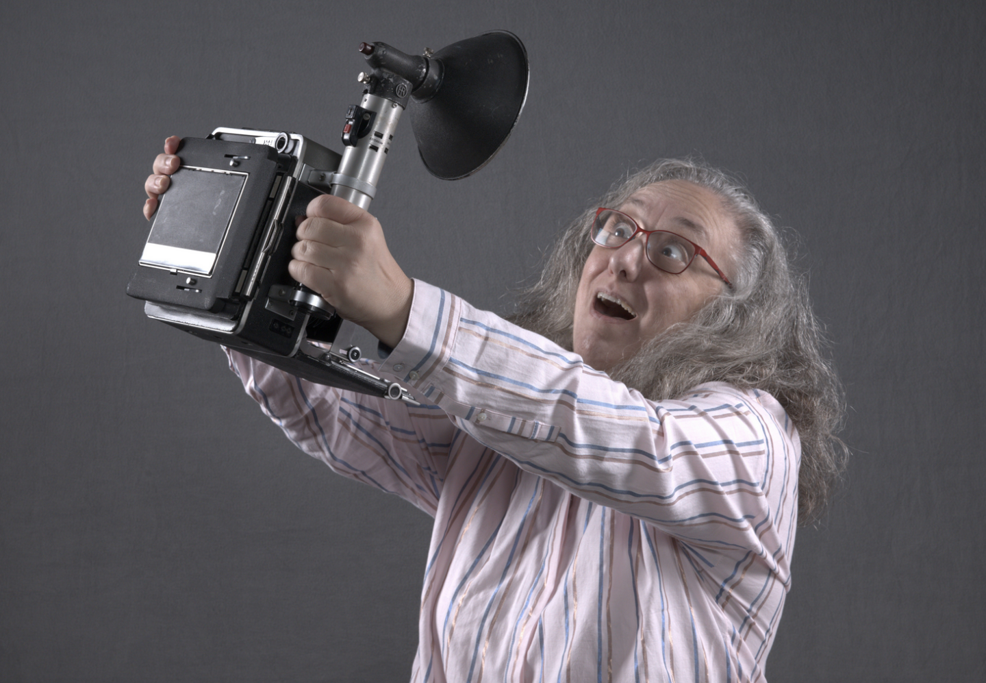 Portrait of Carol Schiraldi holding a press camera as taken by Patrick St Cin