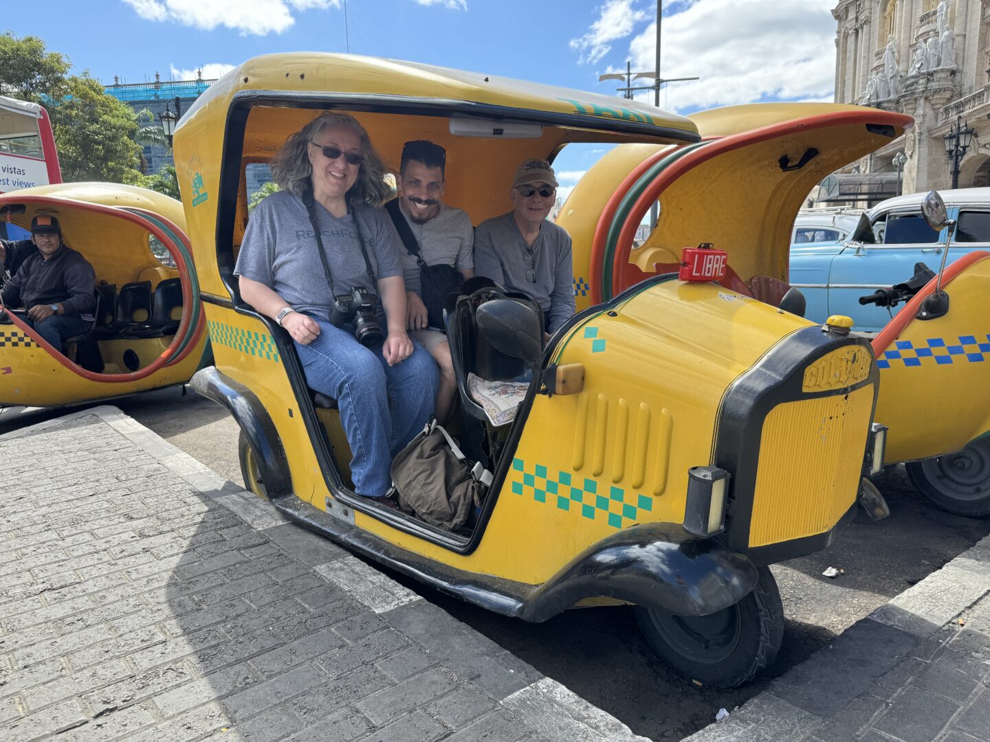 Portrait of Carol Schiraldi along with Wilbur and Mark in the tuk tuk somewhere in Old Havana, Cuba. 

